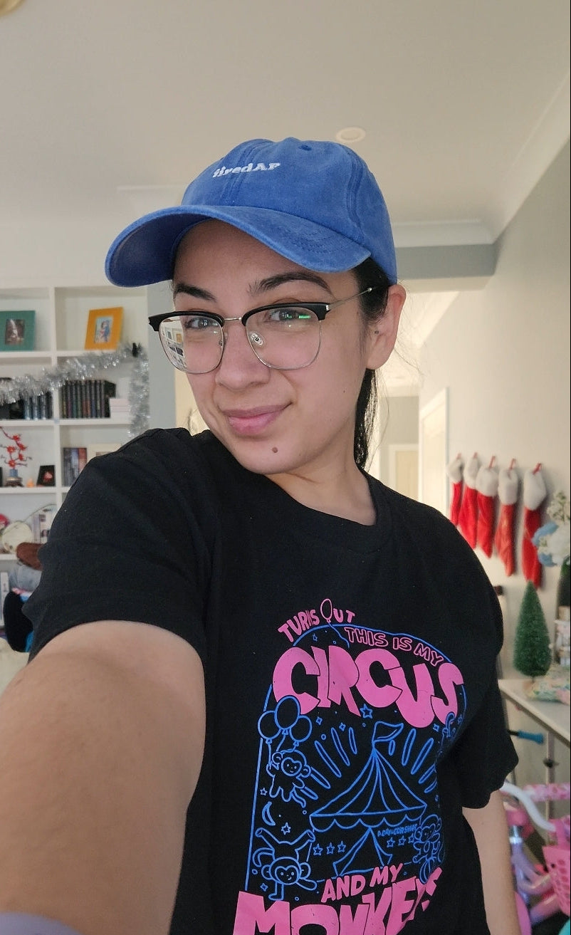 Person wearing a blue cap and black t-shirt with colorful design indoors.